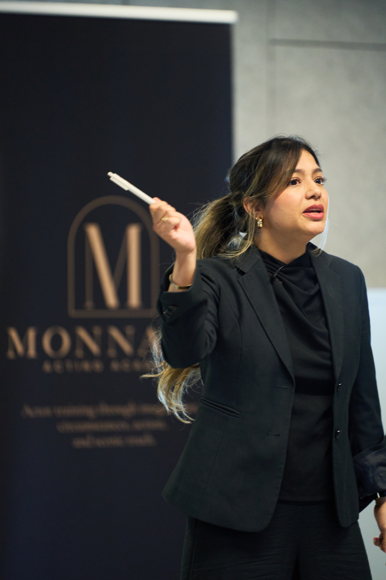 Verónica Coronel teaching at a Monnarc Acting Academy workshop, Monnarc banner behind her